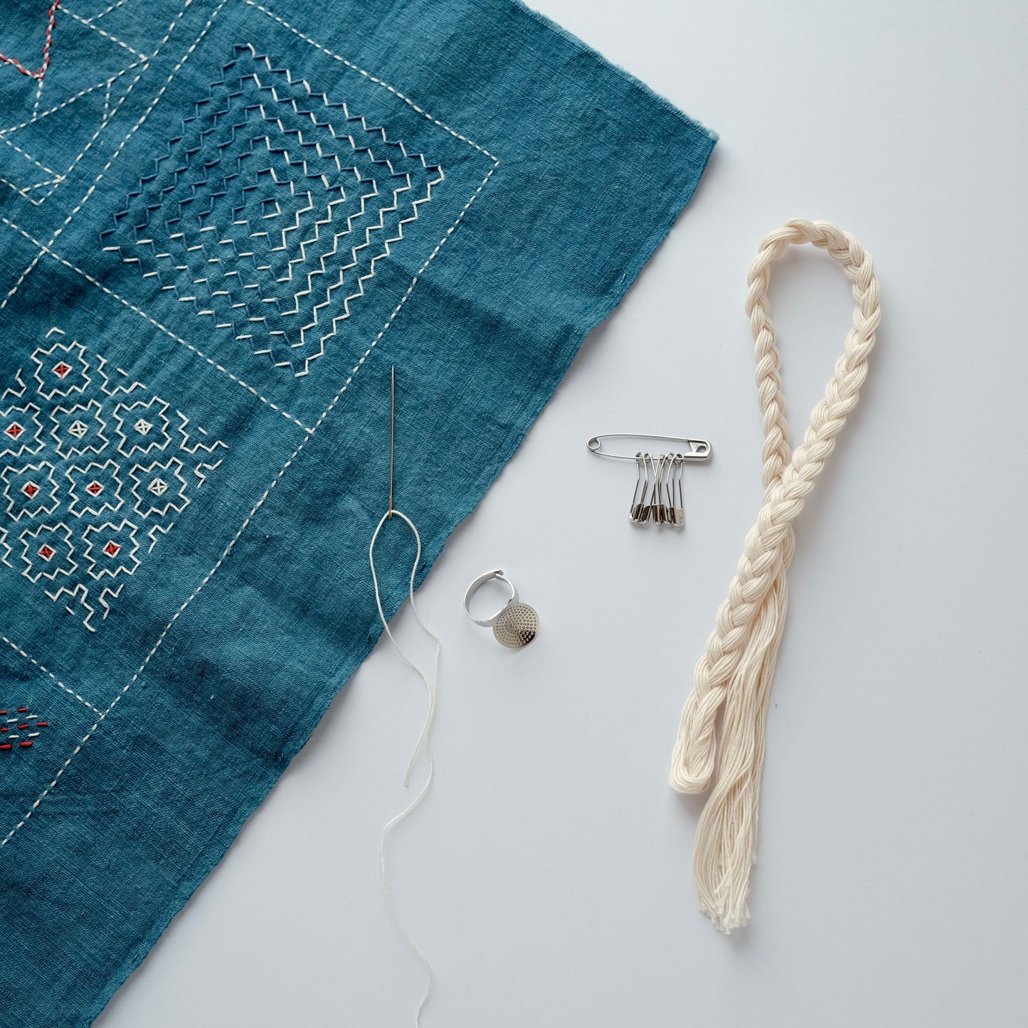 Sashiko tools displayed with a stitched sashiko sample in the background